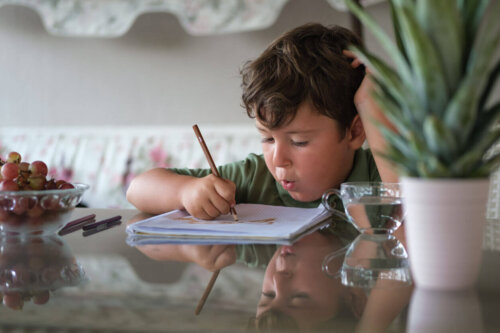 Dreng sidder ved bord og tegner