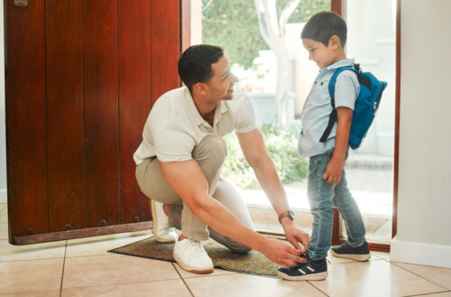 En far binder sit barns sko som en del af at klæde børnene på til skole