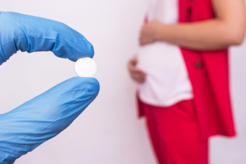 Læge holder pille foran en gravid kvinde