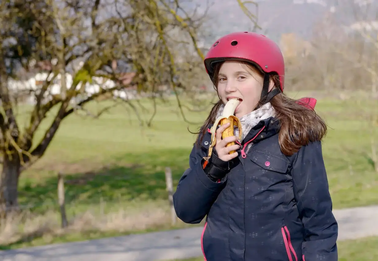 Pige spiser banan, da det hjælper børn med at falde i søvn