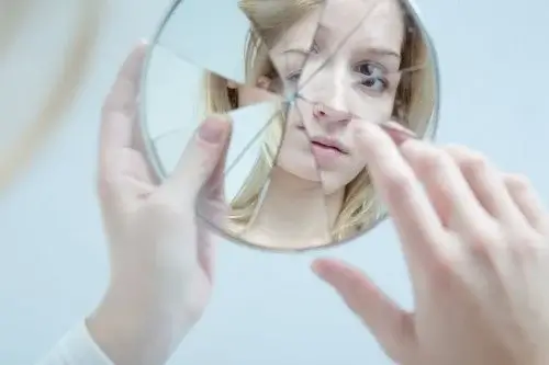 Kvinde ser sig i ødelagt spejl