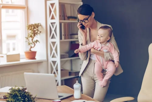 Kvinde snakker i telefon og bærer en baby som eksempel på at være en god mor uden at forsømme karrieren