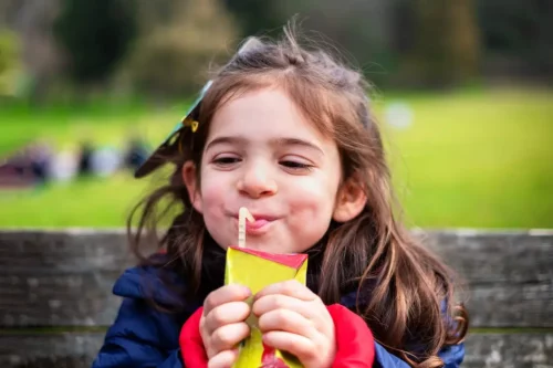 Pige drikker juice, hvilket viser problemet med at reducere sukkerforbruget i børns kost