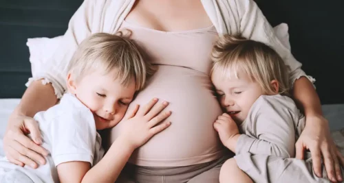 Ældre søskende krammer gravid mave