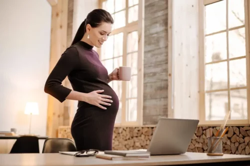 Gravid kvinde står ved sin arbejdsplads