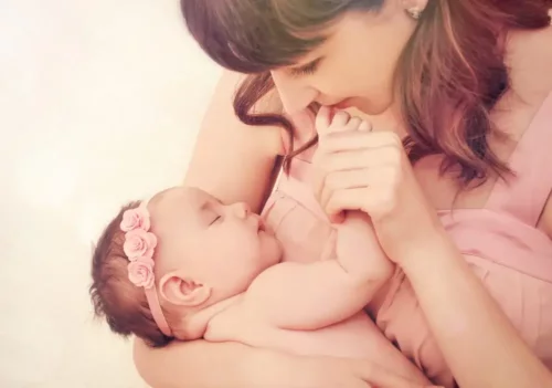 En mor kysser en babyhånd og nyder duften af nyfødte