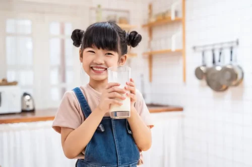 Smilende pige med et stort glas mælk