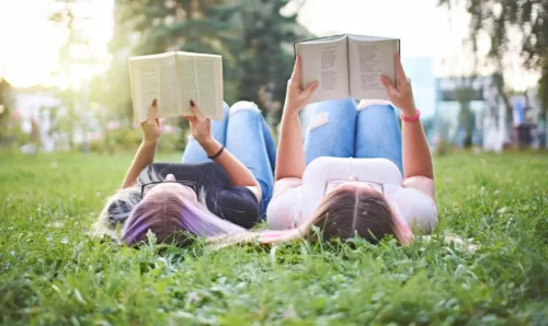 Unge læser liggende på en græsplæne