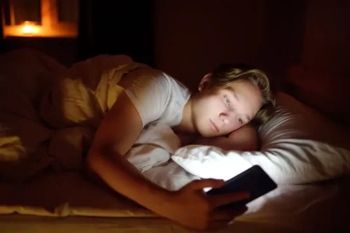 Dreng med telefon i seng repræsenterer mobiltelefoni om natten