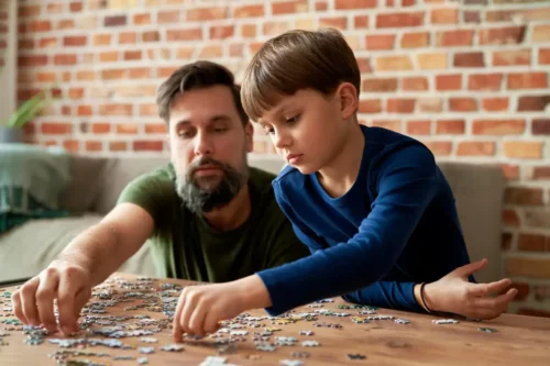 Far og søn lægger puslespil som eksempel på at undervise i geografi derhjemme
