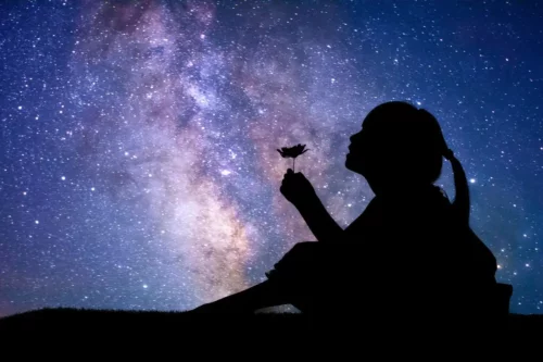Pige sidder foran nattehimmel