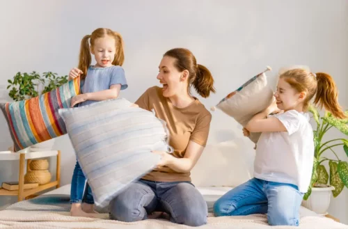 En fleksibel mor er i gang med pudekamp med sine døtre