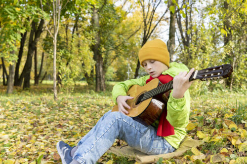 Dreng spiller guitar udenfor som eksempel på udendørs fritidsaktiviteter