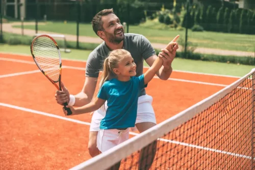 Far og datter spiller tennis sammen