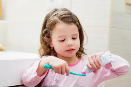 Pige kommer tandpasta på sin tandbørste