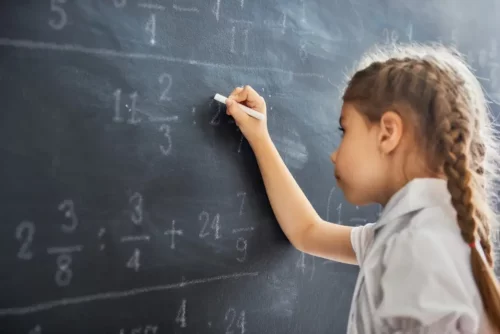 Pige laver regnestykker på tavle