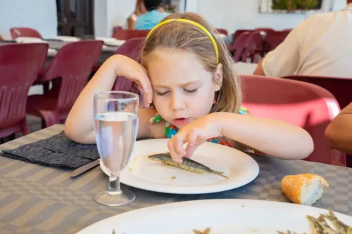 En pige spiser fisk, som er eksempel på fødevarer til børn med anæmi