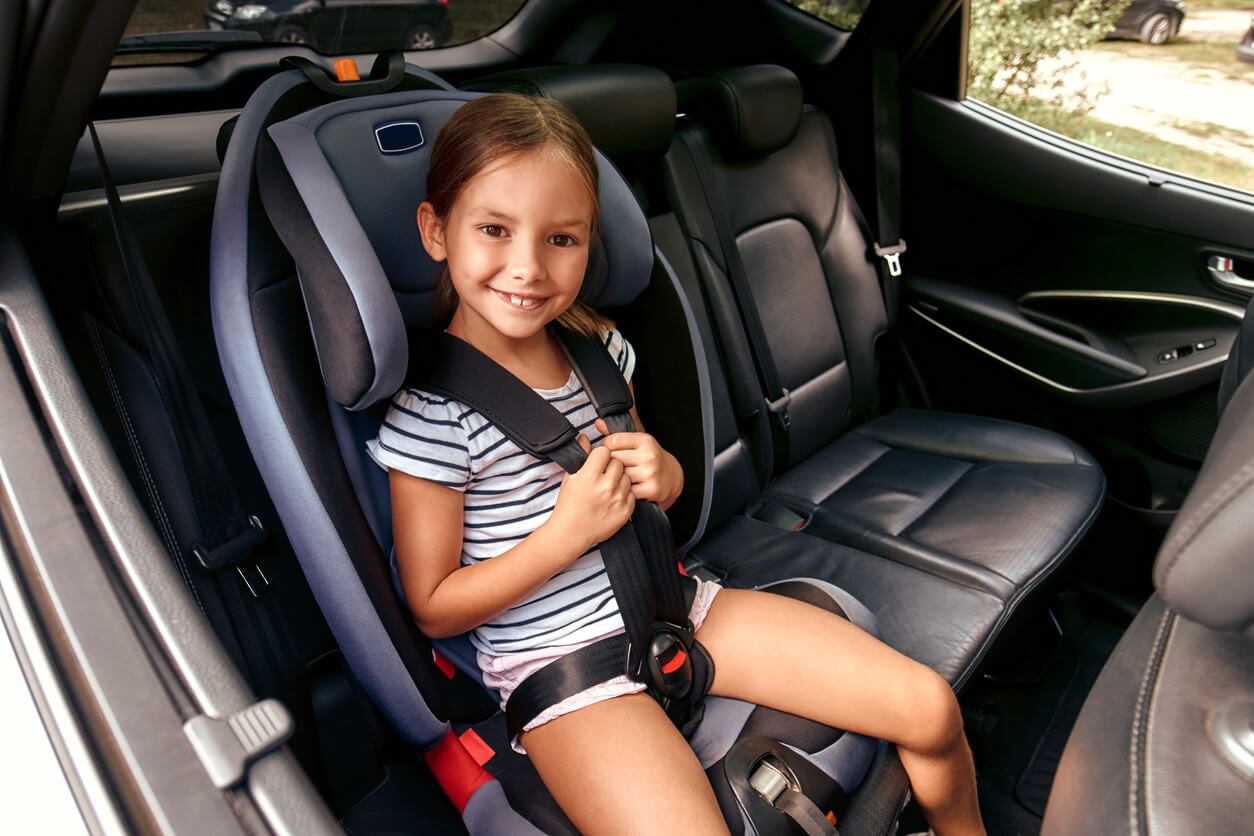 Glad pige i bil repræsenterer sikkerhedsstandarder for autostole