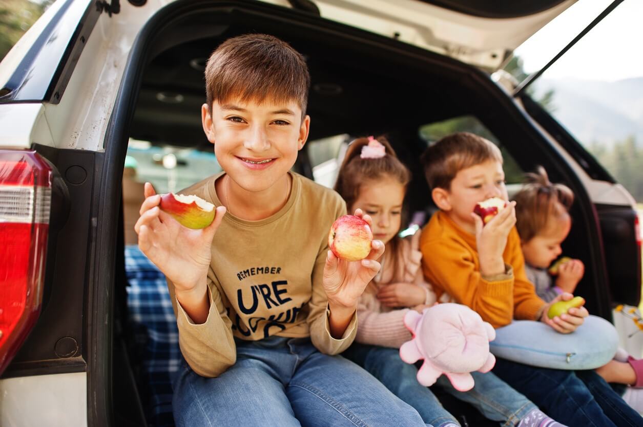 Børn spiser frugt i bagagerum i bil